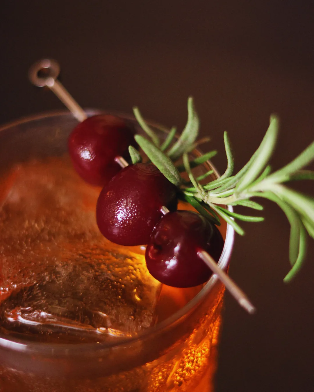 Crimson Oath, a bourbon cocktail with cherries and rosemary over ice, Obscura Tirana