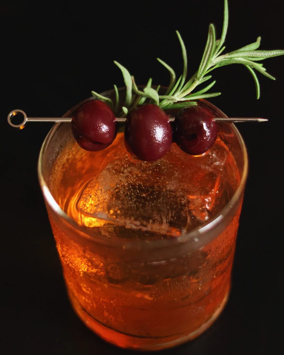 Crimson Oath, a bourbon cocktail with cherries and rosemary over ice, Obscura Tirana